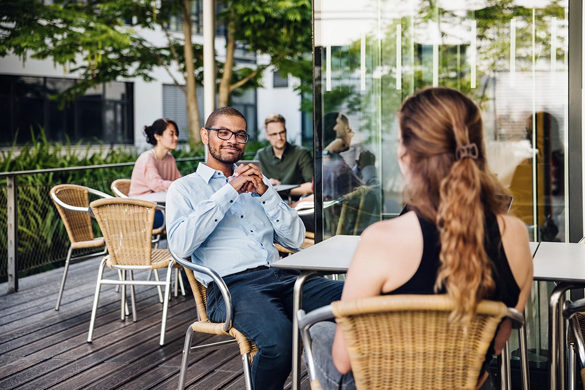 Man with glasses sitting at a cafe outside